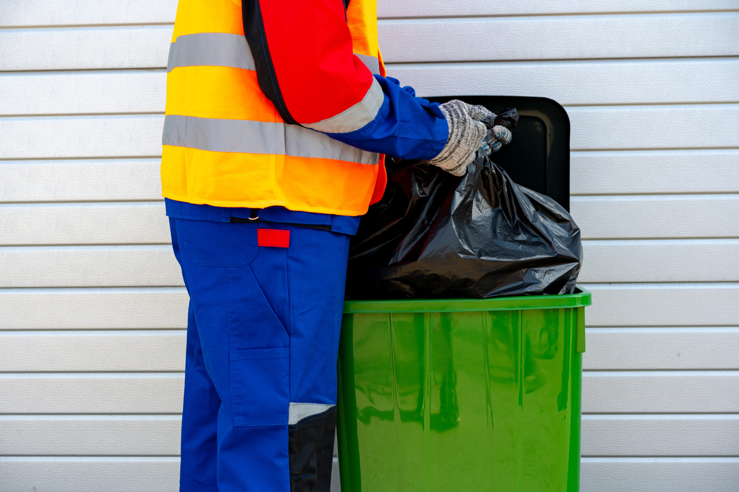 Janitor takes garbage out of trash container outdoors in the street