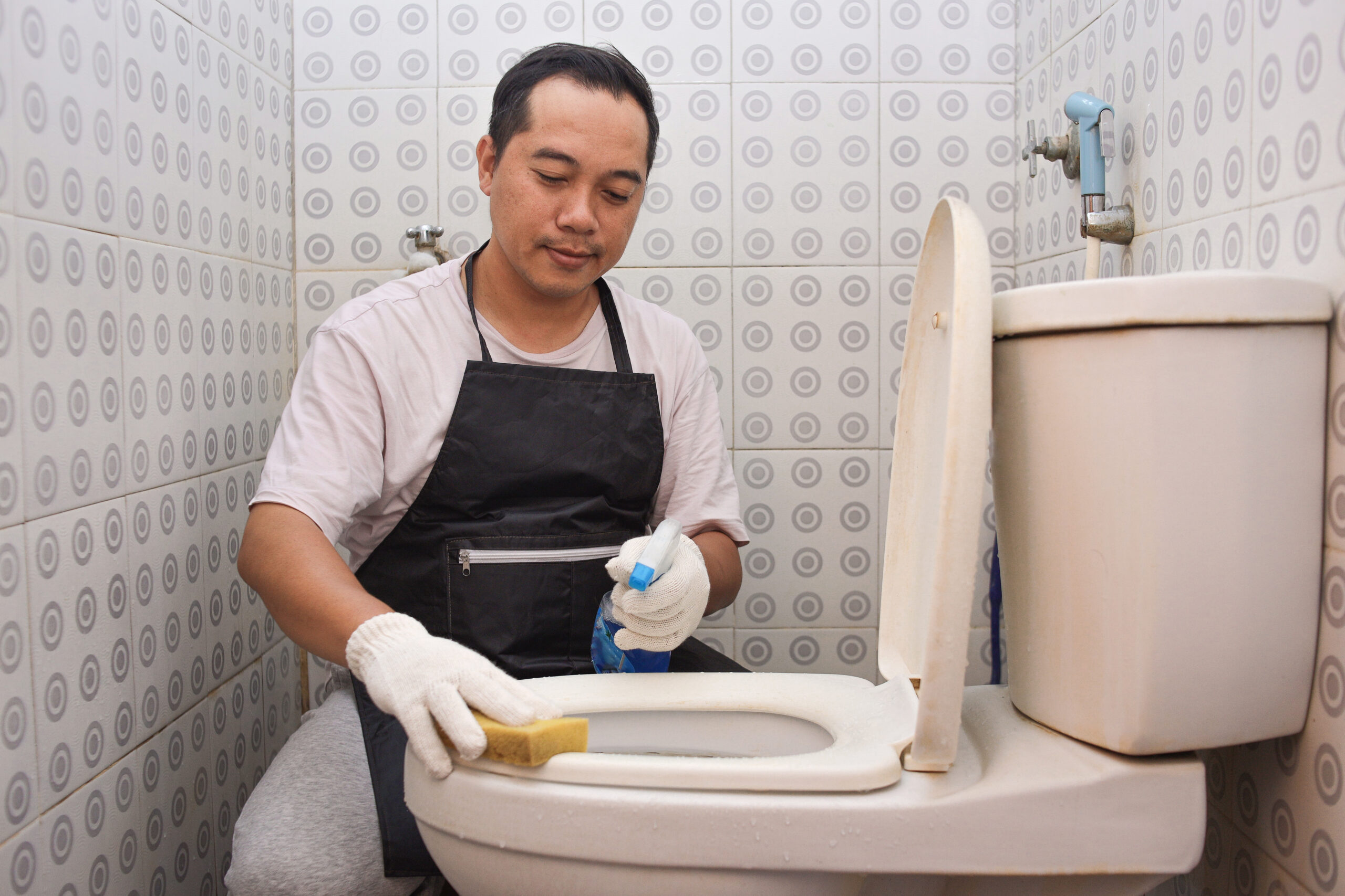 smiling-male-wearing-gloves-brushing-dirty-toilets-bathroom